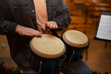 Fototapeta na wymiar A young guy with a beard plays percussion bongos
