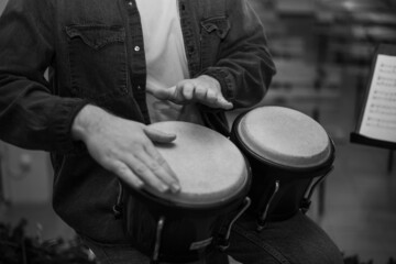 A young guy with a beard plays percussion bongos