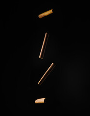 Fragrant brown cinnamon sticks levitating against a black background. Spices, condiments, confectionery, cooking, pastries, restaurant, cafe, hotel, culinary blog. Minimalism. Abstraction.