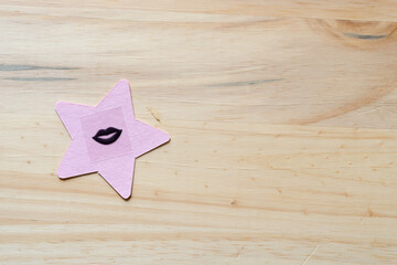 pink star with black lips on plain wood