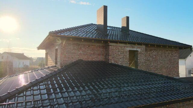Closeup snow guard for safety in winter on house roof top covered with ceramic shingles. Tiled covering of building