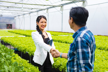 Handshaking between Asian farmer and his new local business entrepreneur inside his hydroponics salad lettuce greenhouse for new partnership concept