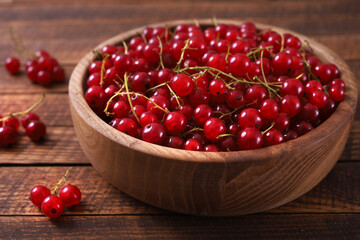 Fresh red currant in wooden bowl on wood table.