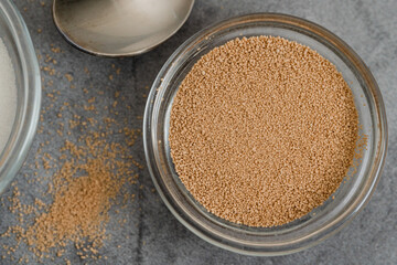 Dry yeast and sugar in a glass bowls close up on grey marble background, copy space, flat lay.