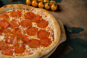 Pizza with salami on a wooden background. Cherry tomatoes.