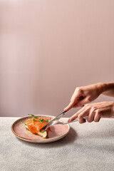 Women's hands with cutlery sandwich with red fish