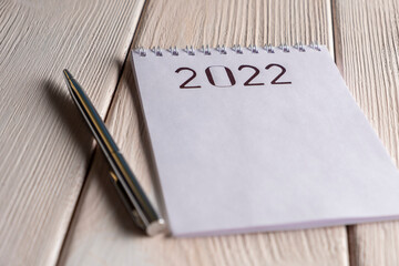 2022 Goals. Notepad with pen on white wooden table.