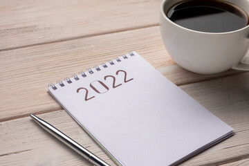 2022 Goals. Notepad with pen on white wooden table.