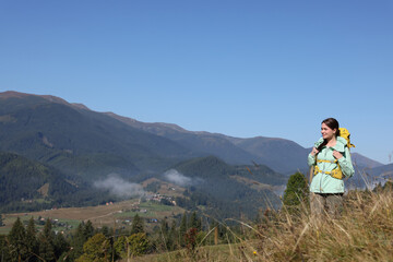 Fototapeta na wymiar Tourist with backpack enjoying view in mountains on sunny day