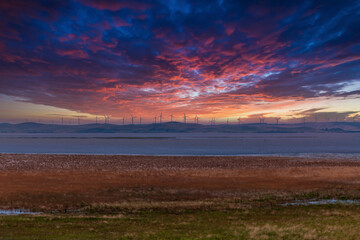 Photograph of Wind Turbines during a cloudy sunset on a hill in Australia