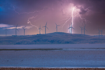 Photograph of Wind Turbines on a hill during a lightning storm