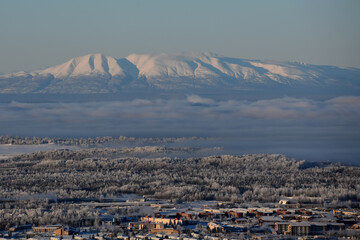 Mount Susitna, also known as Sleeping Lady,  rises 4,396 feet above a frosty Alaska winter landscape with Joint Base Elmendorf-Richardson in the foreground.