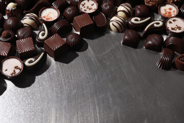 Many different delicious chocolate candies on metal surface. Space for text