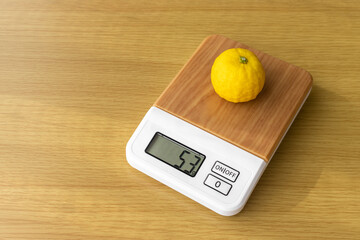 デジタルキッチンスケールで柚子の重さを量るイメージ
