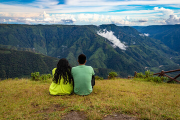 Fototapeta premium isolated young couple spending time together at hilltop with mountain valley and dramatic sky
