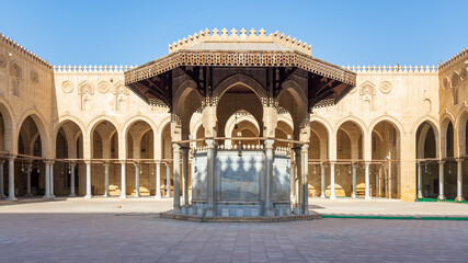 Fototapeta na wymiar Ablution fountain mediating the courtyard of public historic mosque of Sultan al Muayyad, with background of arched corridors surrounding the courtyard, Cairo, Egypt