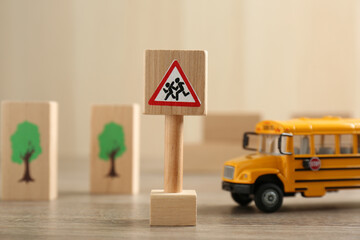 Traffic sign Attention children crossing street and toy bus on wooden table. Passing driving...
