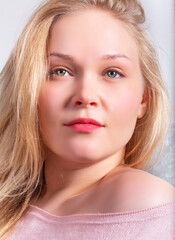 Naklejka premium Portrait of a blonde girl in a pink sweater