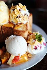 Honey toast with whipped cream and vanilla ice cream and mix berry, strawberry topping on white dish in cafe for cake and bakery homemade shop.