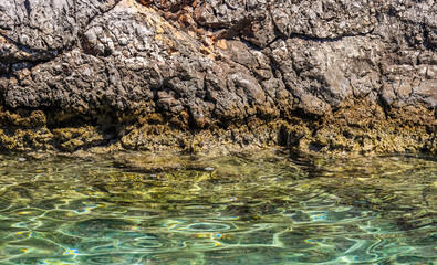 Emerald sea water and natural rocky seashore. Summer vacation and coastal nature concept