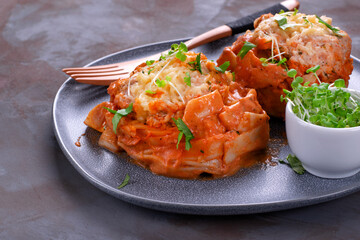 Fettuccine nests with meatball, cheese and tomato sauce served with microgreen on the gray ceramic...
