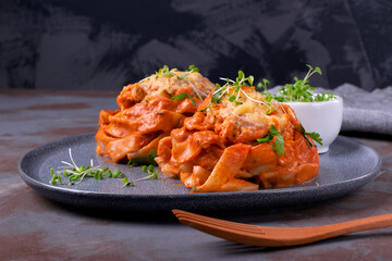 Fettuccine nests with meatball, cheese and tomato sauce served with microgreen on the gray ceramic plate. Hot pasta meal