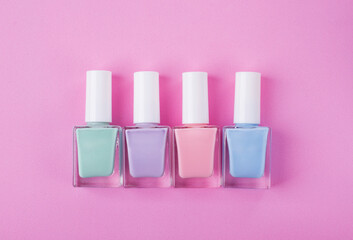 Collection of nail polish of pastel colors in unlabeled vials in a row on pink. Flat lay