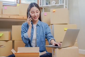 Fototapeta na wymiar Small business entrepreneur SME, asian young woman owner packing product, checking parcel box delivery, using smartphone receive order from customer, working at home office. Merchant online, ecommerce