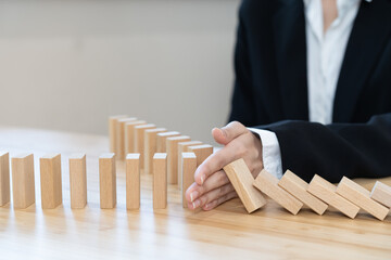 Protection finance, hand of businesswoman stopping falling, block effect collapse domino wooden, Recovery risk business, Management strategy and planning before destroy. Successful intervention.