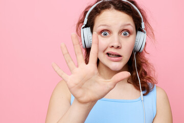 portrait of a young girl in headphones listening to music on a pink background unaltered