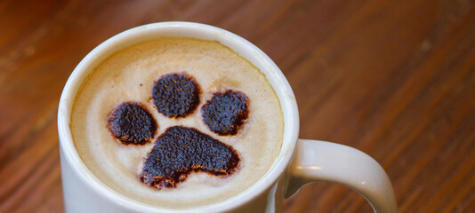 dog paw coffee cat footprint latte art in white mug on wooden table at pet cafe