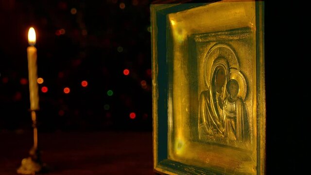 The icon of the Mother of God with the Christ Child is illuminated by a burning candle