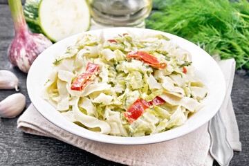 Fettuccine with zucchini and hot peppers in plate on board