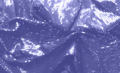 Abstract background with glossy sequins on fabric toned color of the year 2022 Very Peri.