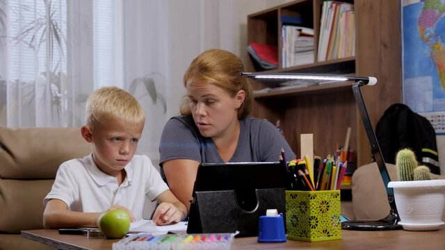 A Frustrated Mom And Her Sad Little Son Hold A Video Conference With A Teacher During Distance Learning During The Coronavirus Outbreak.