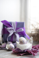 Easter composition with an egg and a gift on a blurred background.