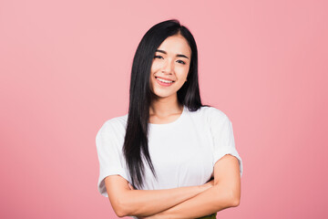 Fototapeta premium Asian happy portrait beautiful cute young woman standing her smile confidence with crossed arms isolated, studio shot on pink background and copy space, Thai female looking to camera