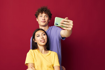 a young couple in colorful T-shirts with a phone isolated background