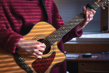 Obraz premium Girl with a guitar in the sunlight through the blinds.
