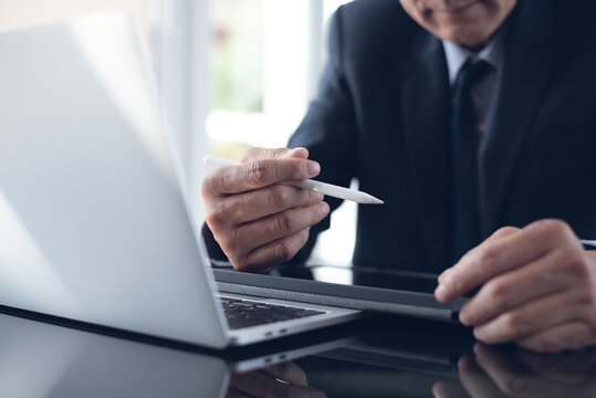 Asian businessman reading e-document, agreement before signing it with stylus pen on digital tablet at office