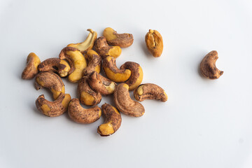 Close up of roasted cashew nuts with skin on white background. Cashew nuts salted with peel- rich in protein, antioxidants, and fiber.