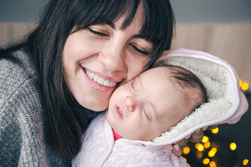 A young mother with a newborn baby girl in her arms.