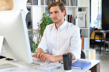Fototapeta premium Young modern business man working using computer while sitting in the office.