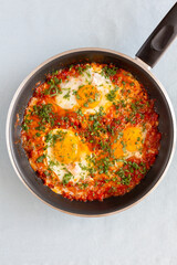 Shakshuka in a pan. Middle eastern traditional dish. Fried eggs with tomatoes, pepper, vegetables and herbs. 