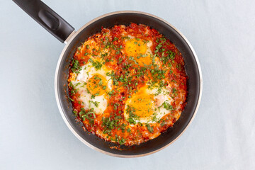 Tasty and Healthy Shakshuka in a Frying Pan. Eggs Poached in Spicy Tomato Pepper Sauce.