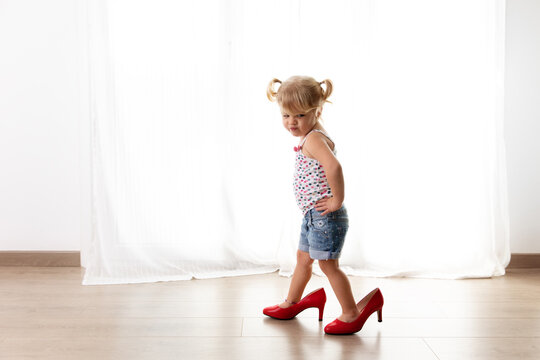 Toddler girl with funny attitude walking with mother's high heels