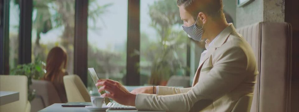 Handsome man in formal clothes working in cafe. Having phone call with client. Wearing striped textile face mask. Entrepreneur working outside office.