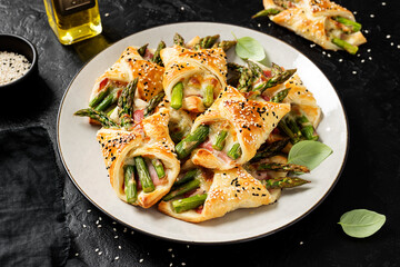 Baked green asparagus with ham and cheese in puff pastry sprinkled with sesame seeds and green...