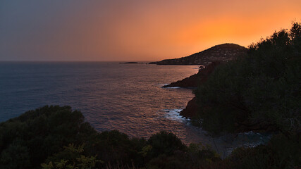 Stunning view of the mediterranean coast east of Saint-Raphael at the French Riviera after sunset with orange colored sky, rough sea.