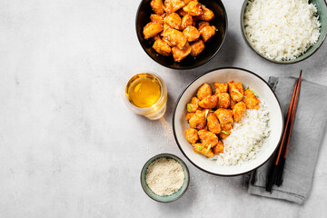 Crispy Honey Sesame Chicken garnished with basmati rice, korean style food. Light gray stone...